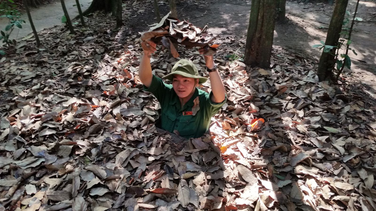 Vietnam2014-738.jpg - En parkbetjent viste hvor svært det var at spotte indgangen til Chu Chi tunneler og hvordan man færdes ud og ind